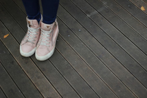 a girl standing on a grey decking with pink shoes and blue jeans