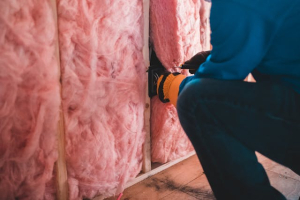 man wearing protective gear fitting pink wall insulation