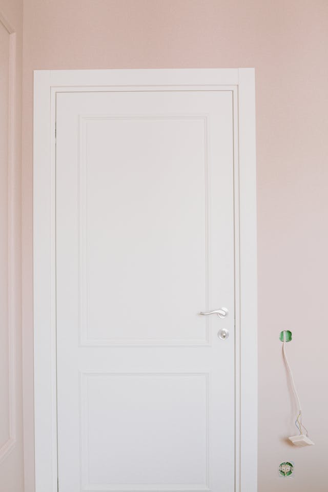 white mdf door with silver handle and a pink surrounding wall